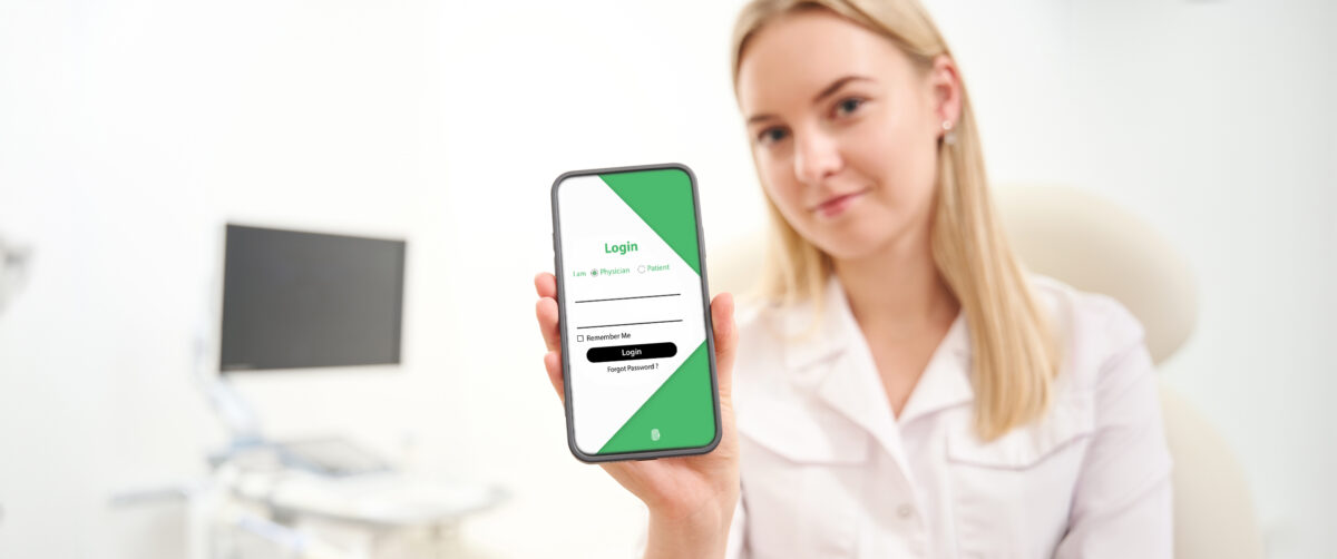 Person holding a smartphone displaying the EndoSoft medical reporting login screen.